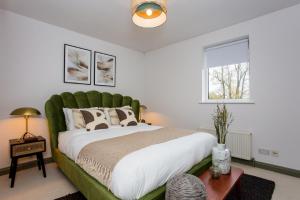 Schlafzimmer mit einem großen Bett mit einem grünen Kopfteil in der Unterkunft The Sparkford Gardens - Lovely 2BDR with Balcony in London