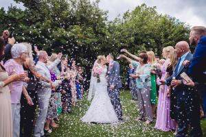 a bride and groom walking down the aisle with confetti at The Rochford Hotel in Southend-on-Sea