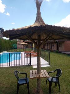 a picnic table and two chairs under a straw umbrella at Posada Entre Dos in Mina Clavero
