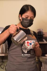 a woman wearing a face mask holding a coffee cup at El Caracol in Popayan