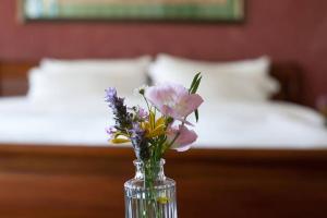 a glass vase with flowers on a table in a bedroom at Darna Bagalil Merlot suite Perfect for couples in Lavon