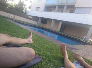 two people laying on the grass next to a swimming pool at Ático spa rural in Alcarraz