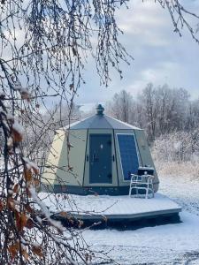 uma tenda cúpula com uma cadeira na neve em North Experience Basecamp em Melen