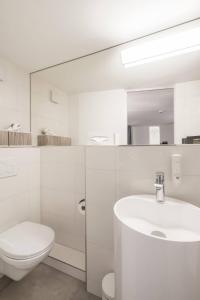 a white bathroom with a toilet and a sink at KoBi Boutique Studios Hirschenplatz in Lucerne