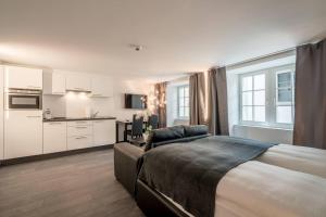 a bedroom with a large bed and a kitchen at KoBi Boutique Studios Hirschenplatz in Lucerne