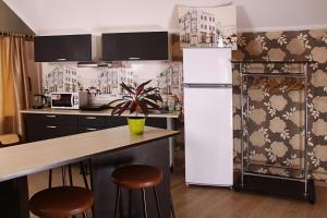 a kitchen with a refrigerator and a counter with stools at Апартаменты Жить просто in Pyatigorsk