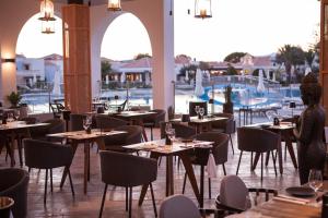 a restaurant with tables and chairs and a pool at Neptune Luxury Resort in Mastichari