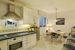 a kitchen with white cabinets and a table with chairs at VCV Villa Magua in Santa Brígida