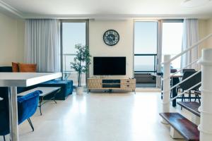 a living room with a tv and a blue couch at Almog Beach Apartments מגדלי חוף הכרמל חיפה in Haifa