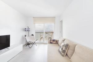 a white living room with a couch and a television at Sunset II in Santa Pola