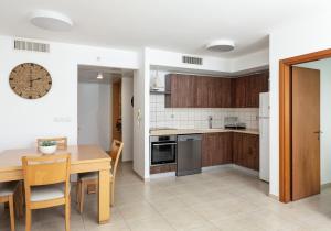 cocina y comedor con mesa y reloj en A white dream by the sea - 2bd lux family apartment en Herzliyya B