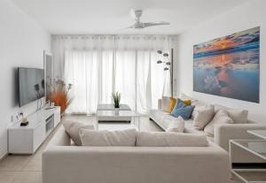 sala de estar blanca con sofá y TV en A white dream by the sea - 2bd lux family apartment en Herzliyya B