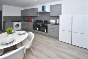 a kitchen with white appliances and a white table and chairs at Townhouse @ 24 Brunswick Place Stoke in Etruria