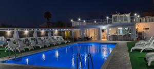 a pool with chairs and a house at night at Roda Pearl Resort in Roda