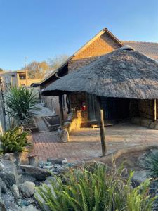 a hut with a thatched roof in a yard at Host Hub Guest House in Kempton Park