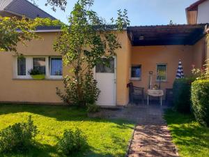 a house with a white door and a table in a yard at Ferien am Bierbach in Eldena