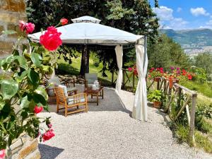 - un kiosque avec une table, des chaises et des fleurs dans l'établissement La Panoramica Gubbio - Maison de Charme - Casette e appartamenti self catering per vacanze meravigliose!, à Gubbio