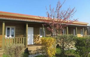 ein Haus mit einer Veranda und einem Baum davor in der Unterkunft Domaine des Epinettes in Saint-Romain-de-Jalionas