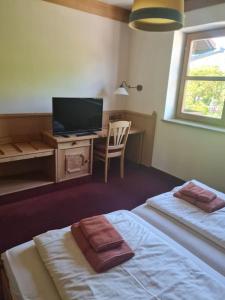 a bedroom with two beds and a desk with a television at Kleines Brauhaus Ingolstadt in Ingolstadt