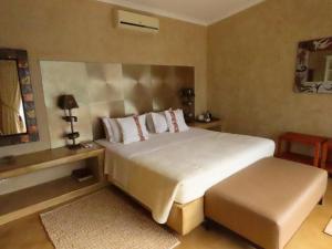 1 dormitorio con cama blanca grande y taburete en Sunset Lodge & Safaris, en Guernsey Nature Reserve
