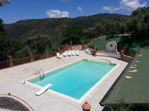 a swimming pool with chairs and a mountain in the background at L'Uliveto in Reitano