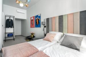 une chambre avec un grand lit blanc avec des oreillers roses dans l'établissement Old Town Residence - Premium Aparthotel, à Cracovie 21 autres photos