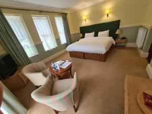a bedroom with a bed and two chairs and a table at The Dower House Hotel in Woodhall Spa +42 photos