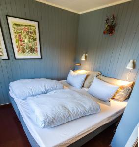 Una cama con dos almohadas blancas encima. en Most photographed house in Reine en Reine