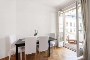 een eetkamer met een zwarte tafel en witte stoelen bij Balcony Oasis Operastreet in Wenen