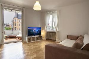 een woonkamer met een bank en een flatscreen-tv bij Balcony Oasis Operastreet in Wenen