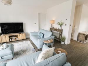 a living room with two blue couches and a tv at 20 Parc Delfryn in Brynteg