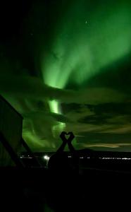 Due persone in piedi sotto l'aurora boreale nel cielo di Akurgerði Guesthouse 2 - Country Life Style a Ölfus