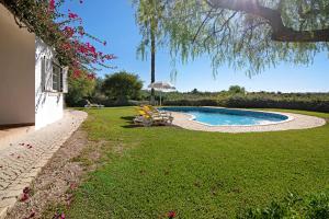 einen Garten mit einem Pool mit Stühlen und einem Sonnenschirm in der Unterkunft Casa do Barrocal in Almancil