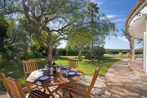 einen Holztisch und Stühle auf einer Terrasse in der Unterkunft Casa do Barrocal in Almancil