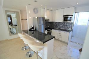 a kitchen with a black counter top and white cabinets at Atico Levante Torre Montecarlo in Benidorm