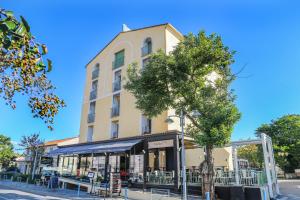 un edificio con un albero di fronte di Hôtel Restaurant Atrachjata ad Aleria