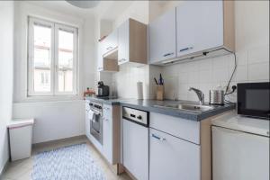 a kitchen with white cabinets and a sink and a tub at Operastreet City Center Santorin in Vienna