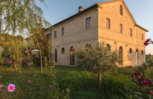 ein altes Backsteingebäude in einem Garten mit Blumen in der Unterkunft Bassarì in Recanati