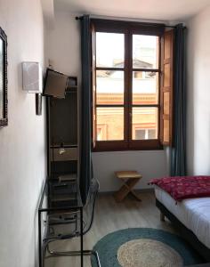 a room with a bed and a window and a chair at Hôtel Croix Baragnon in Toulouse