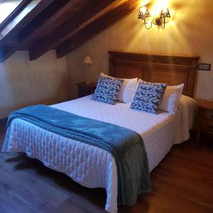 a bedroom with a large bed with blue and white pillows at Puerta al Duraton in Sebúlcor