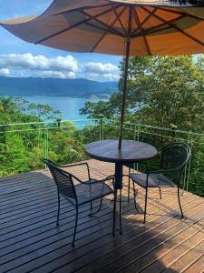 a table and chairs on a deck with an umbrella at Le Refuge Suites in Ilhabela