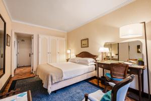 a bedroom with a bed and a desk with a mirror at Hotel Lisboa Plaza - Lisbon Heritage Collection - Avenida in Lisbon +65 photos