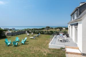 a patio with chairs and a table on the grass at Maison Face à la Mer - Penhors in Pouldreuzic