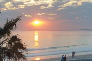 people standing on the beach watching the sunset at Beachfront Apartment in Cape Town