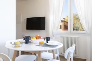 una sala da pranzo bianca con tavolo e sedie bianchi di Palazzo Pedretti Halldis Apartments a Bologna