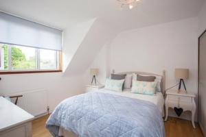 a white bedroom with a bed and a window at Fab-u-Luss in Luss