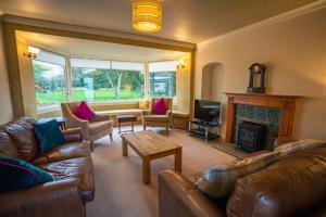 een woonkamer met lederen meubels en een open haard bij The Farmhouse, 6 bed property, Forres in Forres