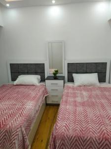 a bedroom with two beds and a dresser with a mirror at شقةفاخرةبجليم على البحر مباشرة in Alexandria