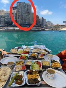 a table with many plates of food on the water at شقةفاخرةبجليم على البحر مباشرة in Alexandria