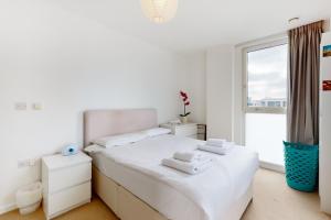 a white bedroom with a bed and a window at Lovely 2 bedroom flat with balcony in Stratford in London